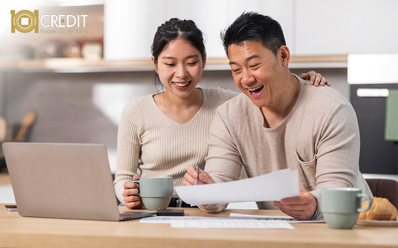 Couple sitting at a kitchen table reviewing documents and a laptop.