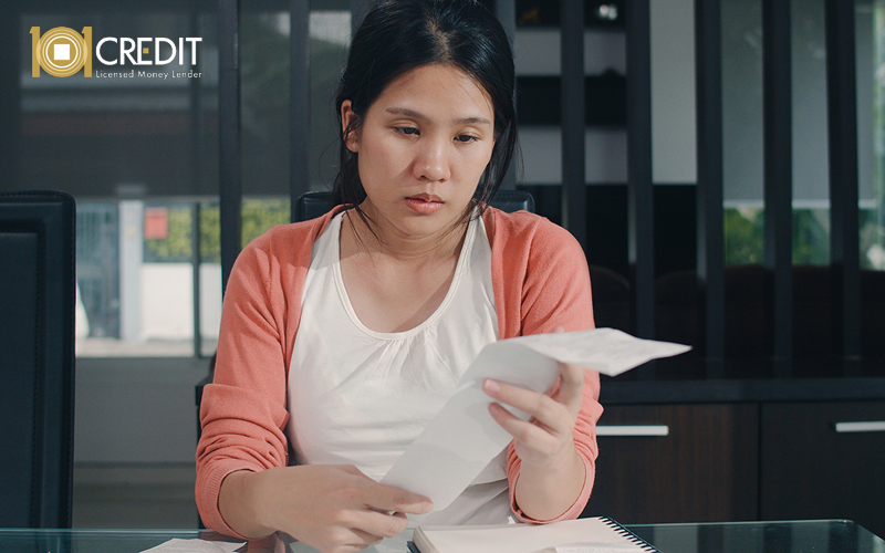 Woman reviewing high bills to manage unforeseen household expenses.