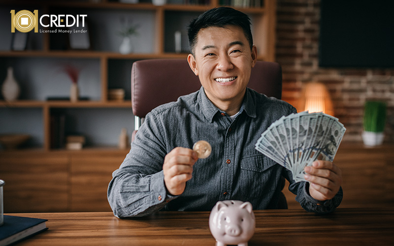 Man smiling while holding a stack of cash and coin.