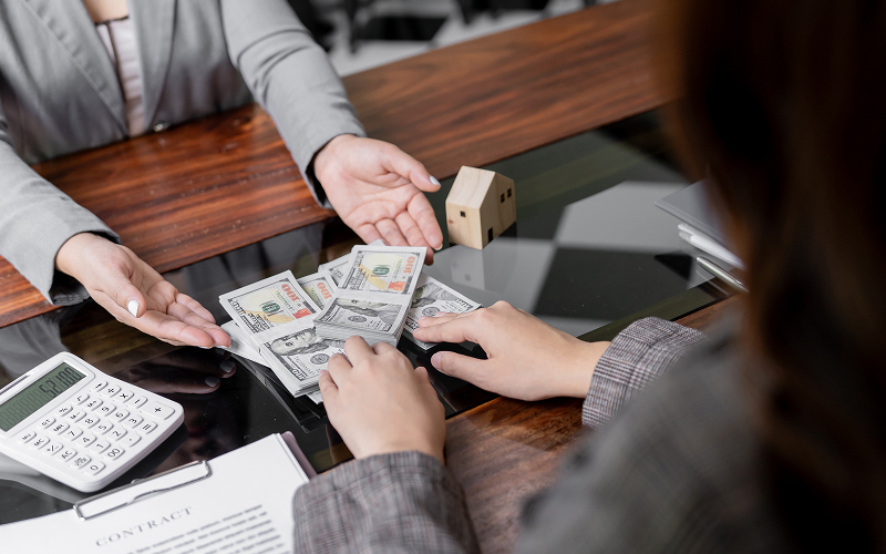 Person receiving cash loan across a desk from a lender.